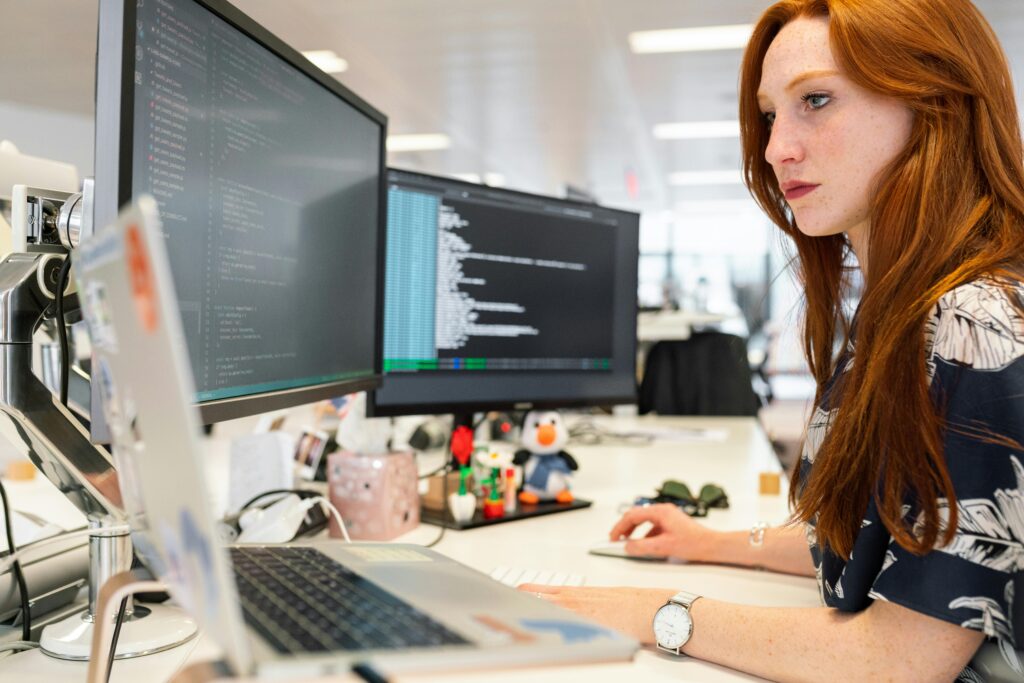 pexels-photo-3861958-3861958-1 A focused female software engineer coding on dual monitors in a modern office.